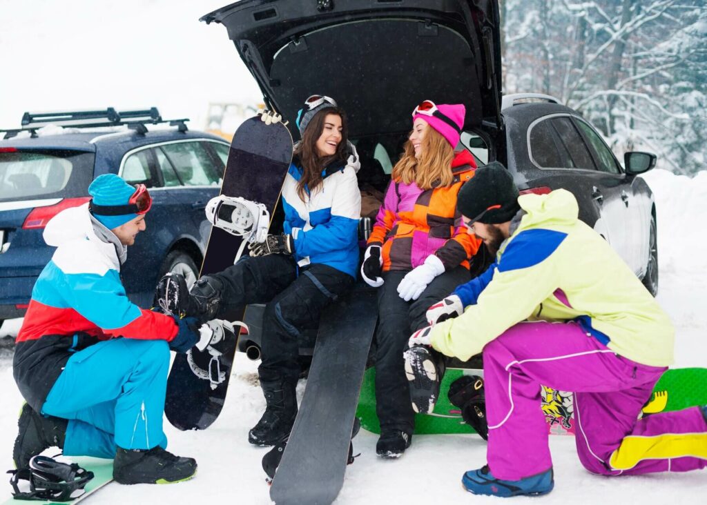 Couples sitting in the trunk, chatting and enjoying snowboarding