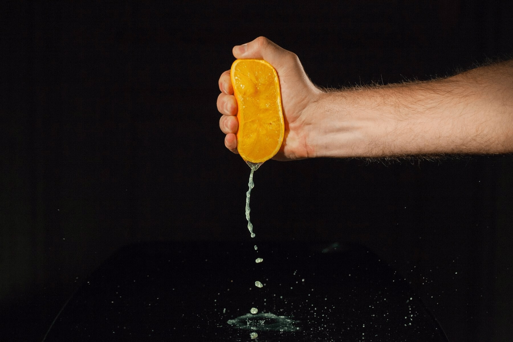 how to make her wet: hand squeezing an orange